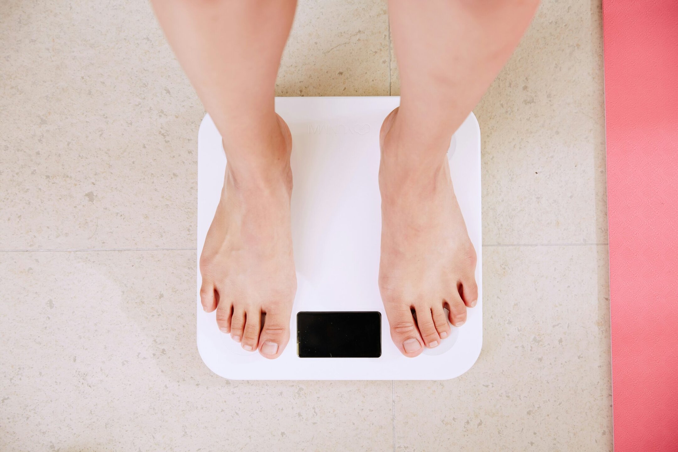 Clear body weight scale with bare feet, showcasing aesthetic wellness and health monitoring services.