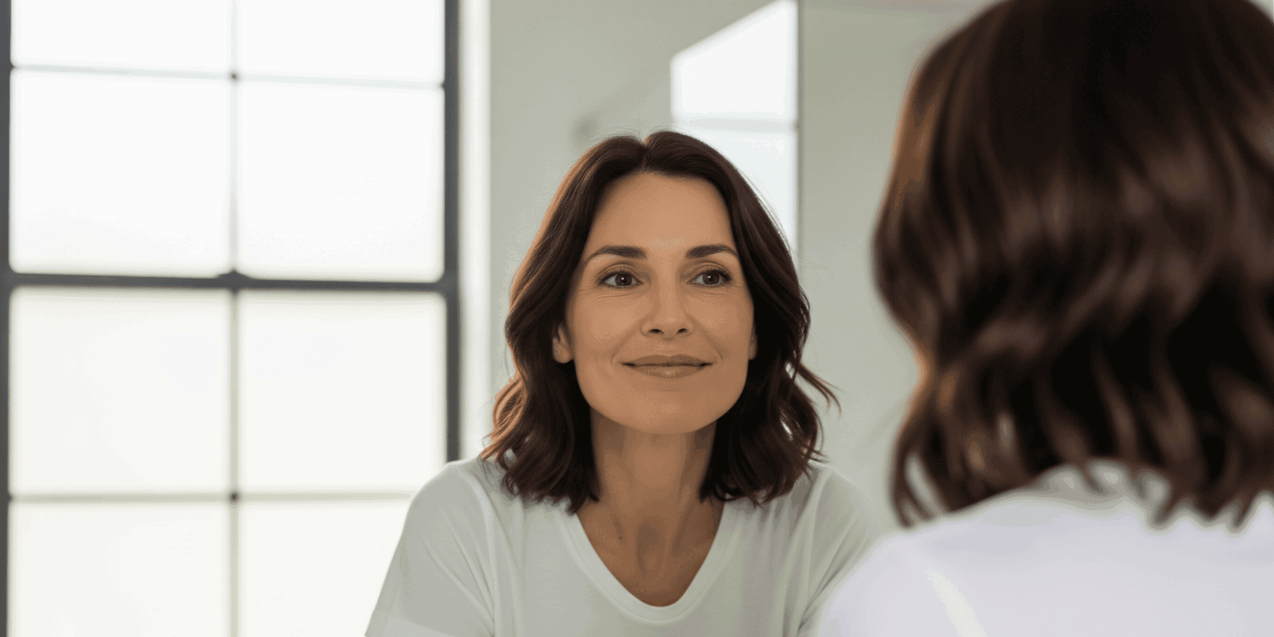 Radiant woman smiling during a consultation at Aetheria Aesthetics & Wellness.