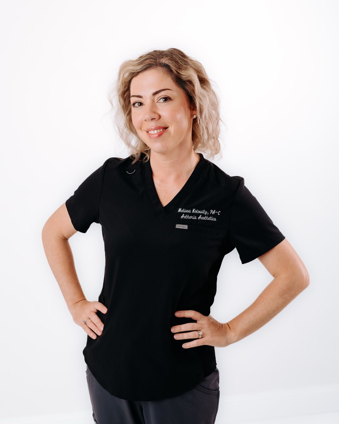 Aetheria Aesthetics & Wellness founder Melissa Kolowitz PA-C smiling in black scrubs.